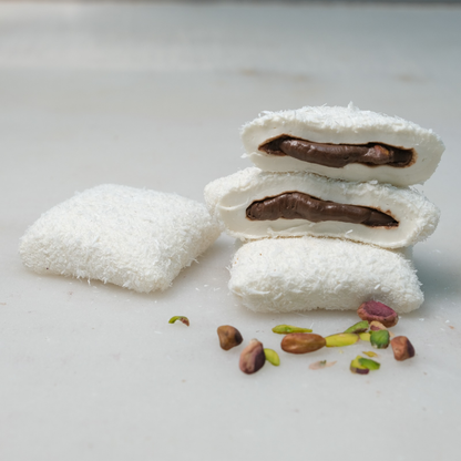 White coconut-covered Turkish Delight pieces with cut pieces showing a dark filling