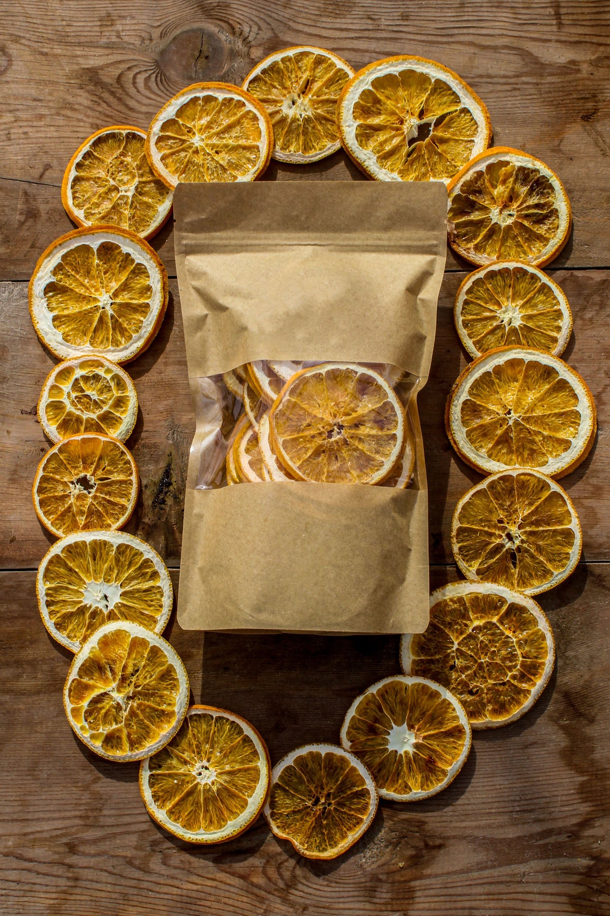 Dried orange slices arranged around a pouch on a wooden table