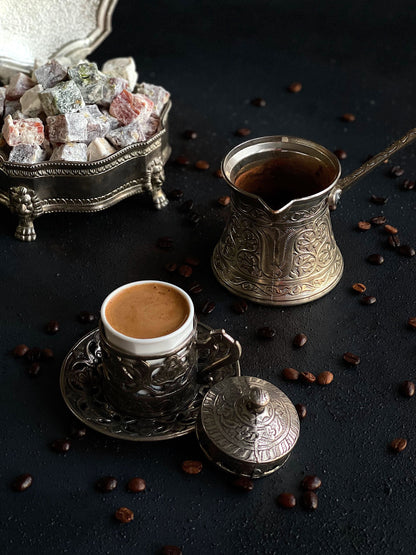 Turkish coffee in a small cup with an ornate cezve and Turkish Delight