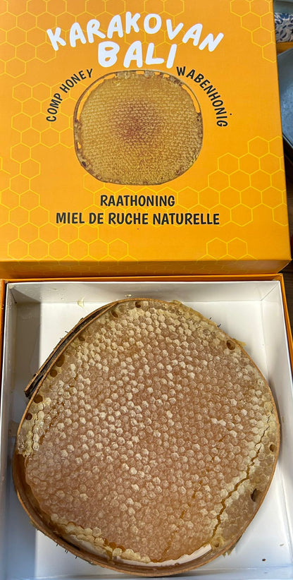 Open orange Karakovan Balı box containing a round honeycomb with the printed lid above