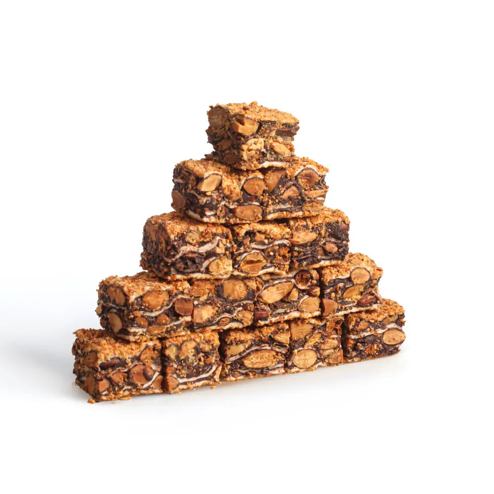 Layered baklava-shaped Turkish Delight pieces with visible almonds and dark chocolate layers on a white background