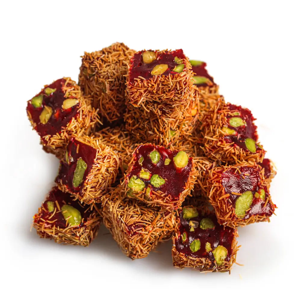 Red Turkish Delight pieces with visible pistachios and a fine golden-brown strand coating